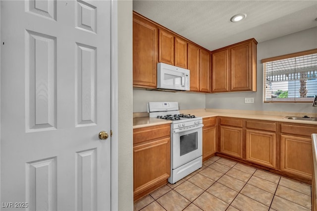 6377 W Haleh Ave, Las Vegas, NV 89141 - kitchen with white appliances, light countertops, brown cabinetry, light tile patterned floors, and recessed lighting