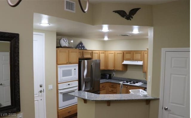 63 E Agate Ave Unit 202, Las Vegas, NV 89123 - kitchen with white appliances, a peninsula, under cabinet range hood, a breakfast bar, and stone countertops