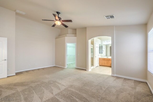 7998 Base Camp Ave, Las Vegas, NV 89178 - unfurnished bedroom featuring arched walkways, light colored carpet, a spacious closet, ensuite bath, and ceiling fan