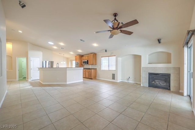 7998 Base Camp Ave, Las Vegas, NV 89178 - unfurnished living room featuring vaulted ceiling, a tiled fireplace, light tile patterned flooring, a ceiling fan, and recessed lighting