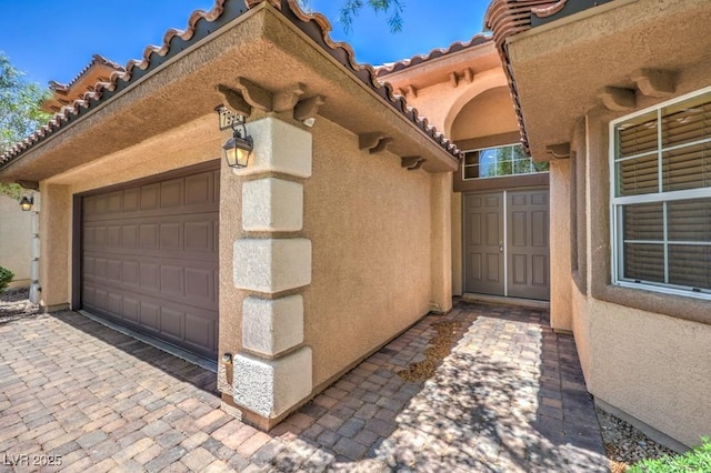 7998 Base Camp Ave, Las Vegas, NV 89178 - doorway to property with stucco siding, a tile roof, and an attached garage