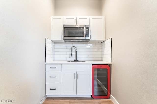 2749 Del Mar Pl, Las Vegas, NV 89169 - indoor bar with stainless steel microwave, beverage cooler, decorative backsplash, and light wood-type flooring