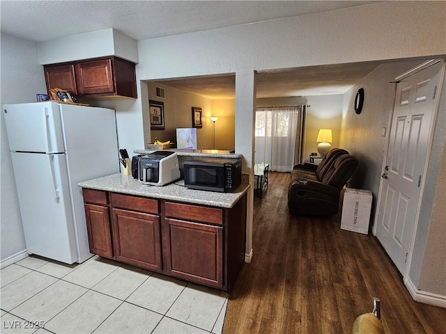 2451 N Rainbow Blvd Unit 1123, Las Vegas, NV 89108 - kitchen featuring freestanding refrigerator, black microwave, open floor plan, light wood-type flooring, and a peninsula