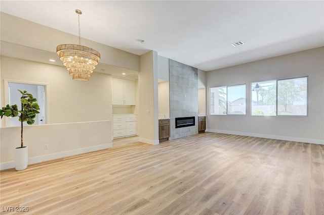 9632 Cherry Canyon Ave, Las Vegas, NV 89129 - unfurnished living room featuring a chandelier, light wood-style floors, and a tiled fireplace