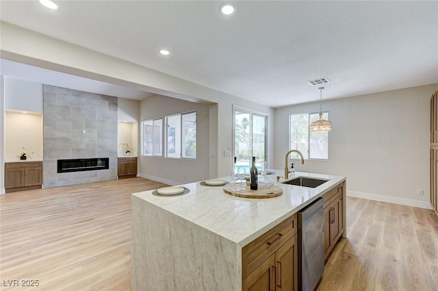 9632 Cherry Canyon Ave, Las Vegas, NV 89129 - kitchen featuring stainless steel dishwasher, light wood-style floors, brown cabinetry, a fireplace, and decorative light fixtures