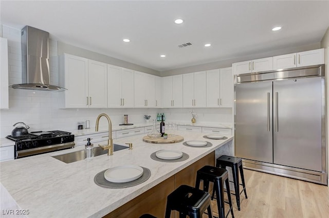 9632 Cherry Canyon Ave, Las Vegas, NV 89129 - kitchen featuring stainless steel built in refrigerator, wall chimney range hood, range, a breakfast bar area, and white cabinetry