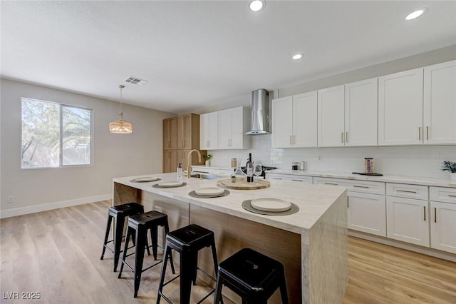 9632 Cherry Canyon Ave, Las Vegas, NV 89129 - kitchen with wall chimney range hood, a kitchen bar, backsplash, light wood-style floors, and recessed lighting