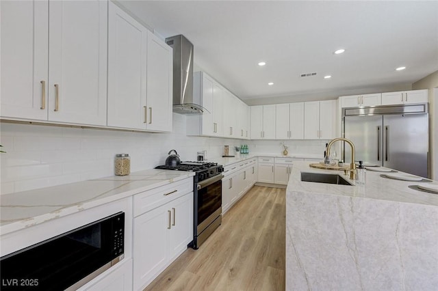 9632 Cherry Canyon Ave, Las Vegas, NV 89129 - kitchen with appliances with stainless steel finishes, wall chimney exhaust hood, light wood finished floors, white cabinets, and recessed lighting
