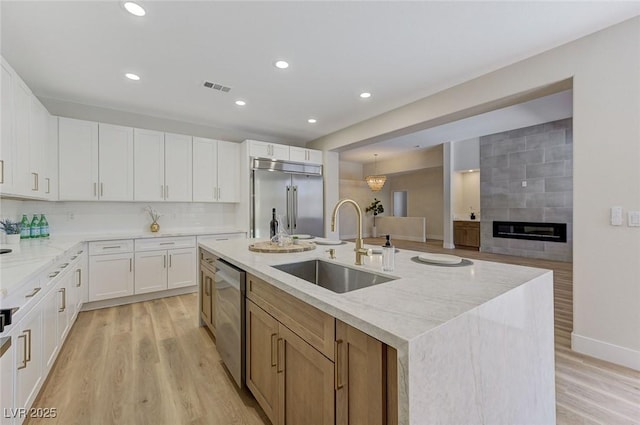 9632 Cherry Canyon Ave, Las Vegas, NV 89129 - kitchen featuring stainless steel appliances, light stone countertops, an island with sink, light wood-type flooring, and recessed lighting