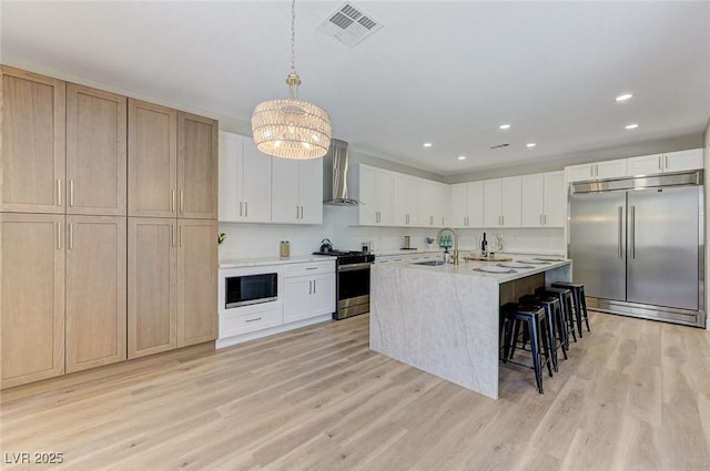 9632 Cherry Canyon Ave, Las Vegas, NV 89129 - kitchen featuring built in appliances, wall chimney range hood, light wood-style floors, a kitchen breakfast bar, and light countertops
