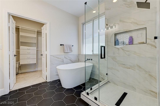 9632 Cherry Canyon Ave, Las Vegas, NV 89129 - bathroom featuring a marble finish shower, tile walls, a freestanding tub, a spacious closet, and tile patterned flooring