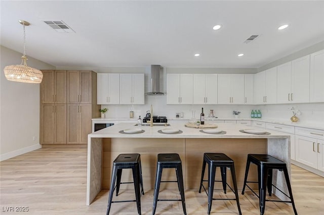9632 Cherry Canyon Ave, Las Vegas, NV 89129 - kitchen with wall chimney exhaust hood, a kitchen breakfast bar, light wood-style flooring, a kitchen island with sink, and recessed lighting