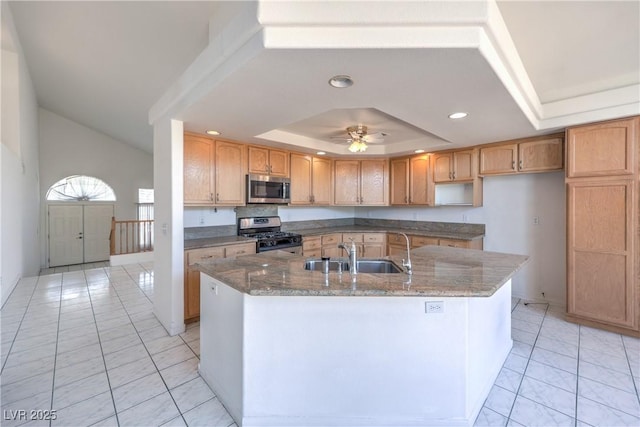 2728 Aspen Wood Ave, Henderson, NV 89074 - kitchen featuring appliances with stainless steel finishes, a raised ceiling, dark stone counters, a center island with sink, and recessed lighting