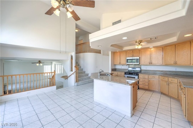 2728 Aspen Wood Ave, Henderson, NV 89074 - kitchen with stainless steel appliances, ceiling fan, light tile patterned flooring, a tray ceiling, and light brown cabinetry