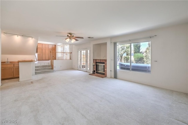 2728 Aspen Wood Ave, Henderson, NV 89074 - unfurnished living room featuring ceiling fan, light carpet, a brick fireplace, and stairway