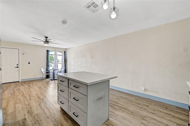 1804 David Ave, Las Vegas, NV 89101 - kitchen featuring ceiling fan, light wood-style floors, a center island, gray cabinetry, and light countertops