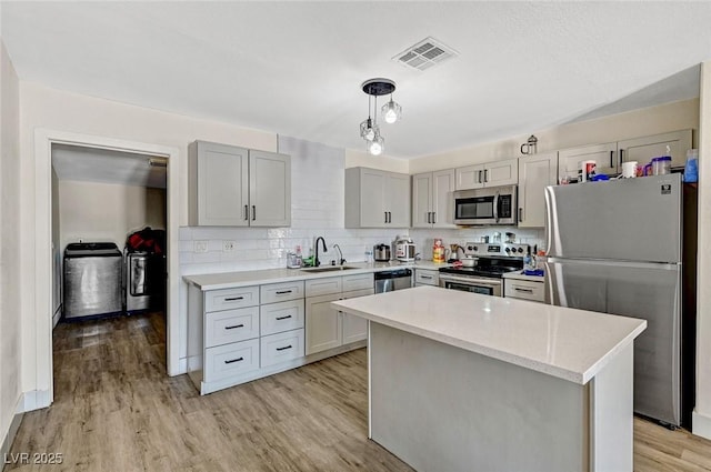 1804 David Ave, Las Vegas, NV 89101 - kitchen with appliances with stainless steel finishes, washer and dryer, light countertops, light wood finished floors, and backsplash