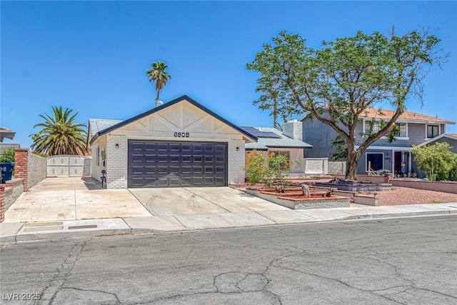 6808 Waterhen Cir, Las Vegas, NV 89108 - view of front facade with roof mounted solar panels, an attached garage, concrete driveway, brick siding, and a gate