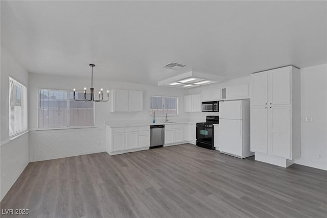 6808 Waterhen Cir, Las Vegas, NV 89108 - kitchen featuring appliances with stainless steel finishes, a chandelier, wood finished floors, white cabinetry, and light countertops