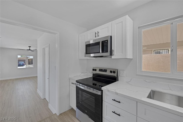 2005 Jansen Ave, Las Vegas, NV 89101 - kitchen featuring stainless steel appliances, light stone counters, white cabinetry, light wood finished floors, and a ceiling fan