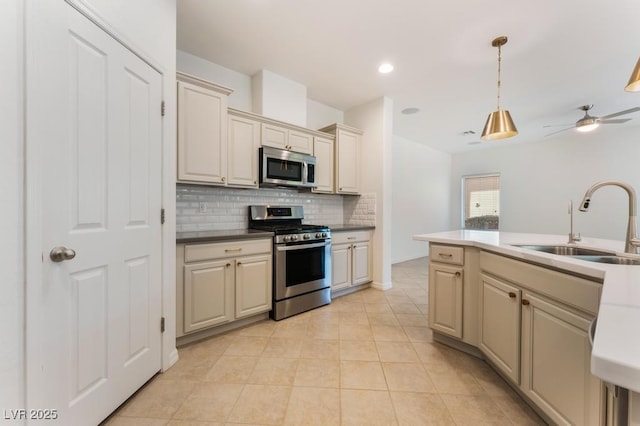 5735 Oak Bend Dr, Las Vegas, NV 89135 - kitchen with stainless steel appliances, decorative backsplash, cream cabinetry, hanging light fixtures, and a ceiling fan