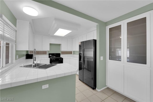 638 Ribbon Grass Ave, Las Vegas, NV 89183 - kitchen featuring refrigerator with ice dispenser, black gas stove, light tile patterned floors, tile counters, and white cabinetry