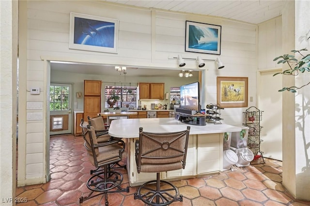 55 Siddall Ave, Las Vegas, NV 89183 - kitchen featuring brown cabinets, wooden walls, light countertops, a breakfast bar, and a peninsula