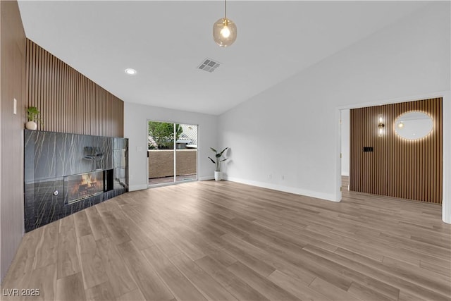 9412 Mount Cherie Ave Unit 102, Las Vegas, NV 89129 - unfurnished living room with a tile fireplace, light wood-type flooring, lofted ceiling, and recessed lighting