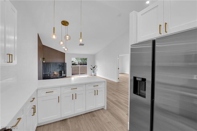 9412 Mount Cherie Ave Unit 102, Las Vegas, NV 89129 - kitchen featuring stainless steel fridge, lofted ceiling, white cabinets, a peninsula, and light countertops
