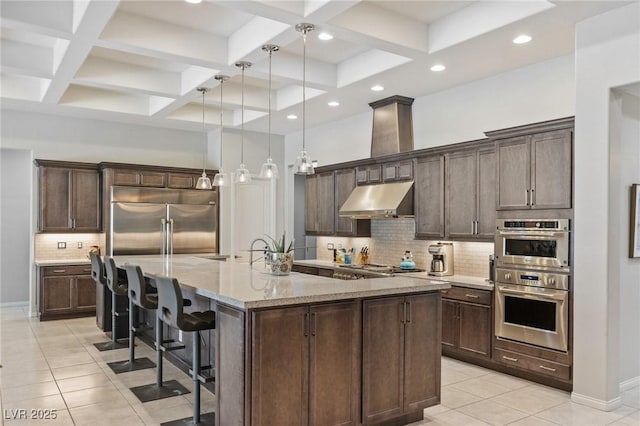 6315 Carol Butte Ct, Las Vegas, NV 89141 - kitchen with under cabinet range hood, appliances with stainless steel finishes, light tile patterned floors, coffered ceiling, and tasteful backsplash