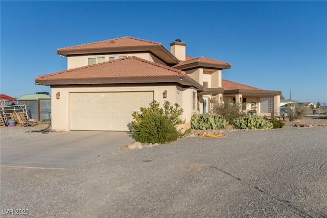 3821 Tumbleweed Ave, Pahrump, NV 89048 - mediterranean / spanish house featuring an attached garage, driveway, stucco siding, a chimney, and a tile roof