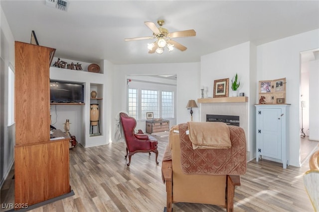 3821 Tumbleweed Ave, Pahrump, NV 89048 - living area featuring light wood-style flooring, ceiling fan, and a glass covered fireplace