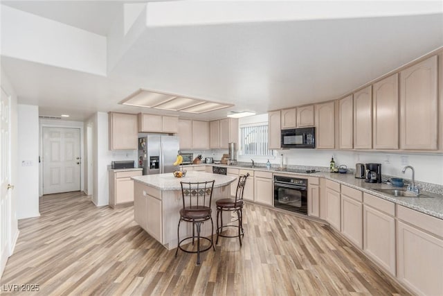 3821 Tumbleweed Ave, Pahrump, NV 89048 - kitchen featuring black appliances, a kitchen island, light wood finished floors, and a breakfast bar