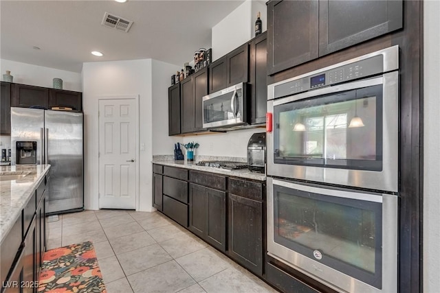 889 Harbor Ave, Henderson, NV 89002 - kitchen with stainless steel appliances, light tile patterned floors, light stone counters, dark brown cabinets, and recessed lighting
