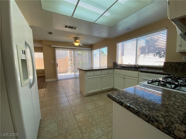 7604 Cruz Bay Ct, Las Vegas, NV 89128 - kitchen featuring white refrigerator with ice dispenser, a peninsula, light tile patterned flooring, ceiling fan, and white cabinetry