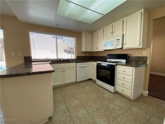 7604 Cruz Bay Ct, Las Vegas, NV 89128 - kitchen with white appliances, white cabinetry, dark stone counters, and a peninsula