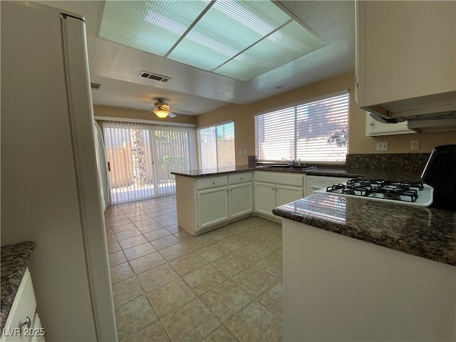 7604 Cruz Bay Ct, Las Vegas, NV 89128 - kitchen featuring a peninsula, a ceiling fan, range, white cabinets, and dark stone countertops