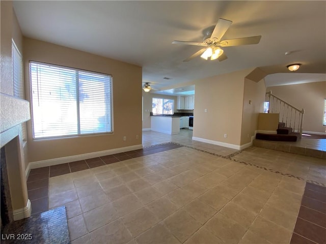 7604 Cruz Bay Ct, Las Vegas, NV 89128 - unfurnished living room with ceiling fan, stairs, tile patterned floors, arched walkways, and a fireplace