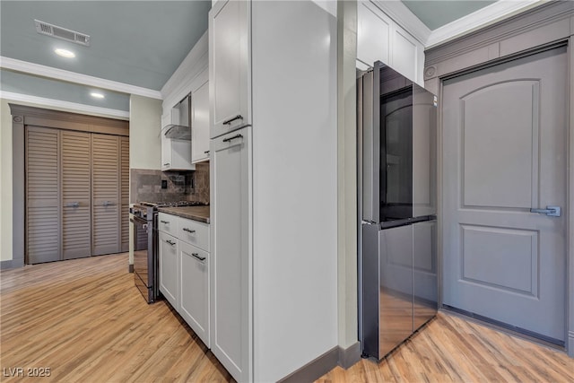 4272 Sheppard Dr, Las Vegas, NV 89121 - kitchen with stainless steel appliances, dark countertops, white cabinets, light wood-style floors, and crown molding