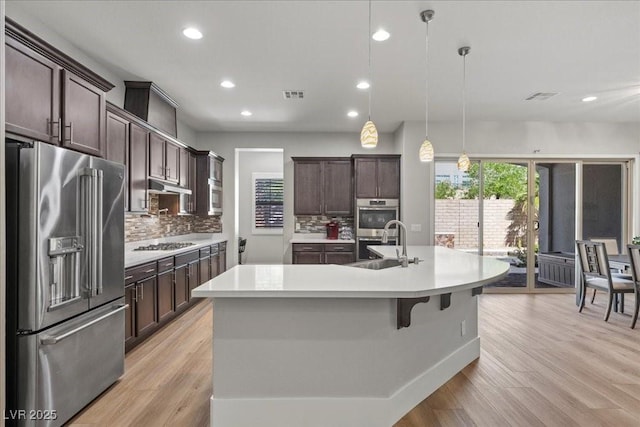251 Castellari Dr, Las Vegas, NV 89138 - kitchen with stainless steel appliances, recessed lighting, light countertops, dark brown cabinets, and a center island with sink
