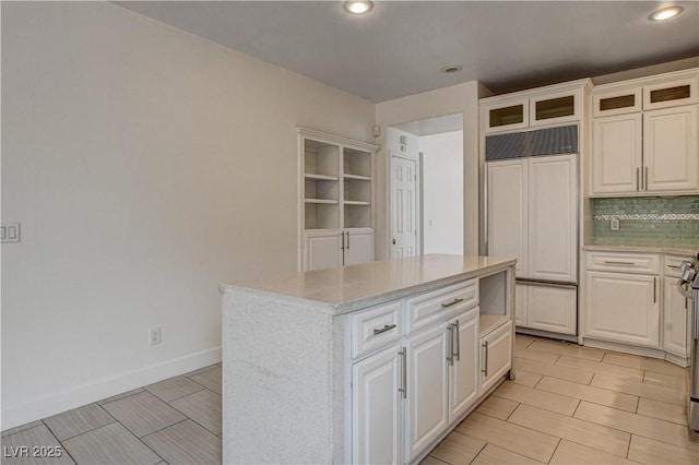 3200 Ridgecliff St, Las Vegas, NV 89129 - kitchen featuring paneled fridge, a kitchen island, decorative backsplash, white cabinets, and glass insert cabinets