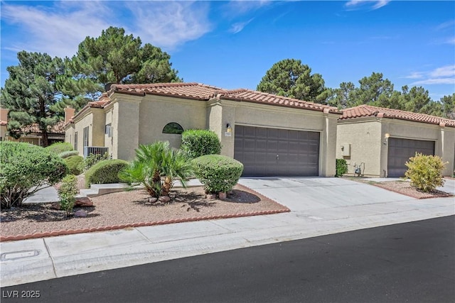 7909 Canoe Ln, Las Vegas, NV 89145 - mediterranean / spanish home featuring an attached garage, a tile roof, stucco siding, and driveway