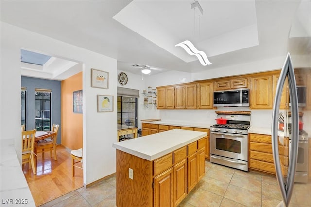 7909 Canoe Ln, Las Vegas, NV 89145 - kitchen featuring a raised ceiling, appliances with stainless steel finishes, light countertops, a center island, and brown cabinets