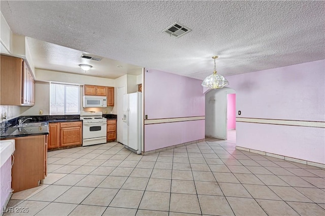 5121 Gains Mill St, Las Vegas, NV 89122 - kitchen with white appliances, dark countertops, a textured ceiling, hanging light fixtures, and brown cabinetry