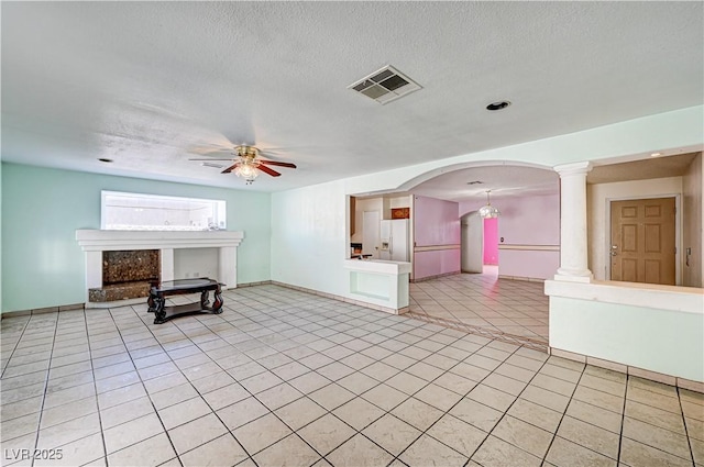 5121 Gains Mill St, Las Vegas, NV 89122 - unfurnished living room with ceiling fan, light tile patterned flooring, a fireplace, a textured ceiling, and decorative columns
