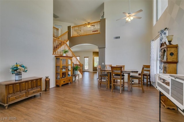 6109 Sandstone Mesa Dr, Las Vegas, NV 89130 - dining space featuring arched walkways, a high ceiling, a ceiling fan, light wood finished floors, and stairway