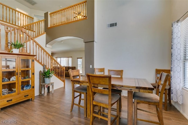 6109 Sandstone Mesa Dr, Las Vegas, NV 89130 - dining room featuring arched walkways, a towering ceiling, stairs, wood finished floors, and healthy amount of natural light