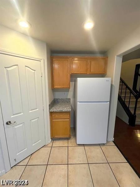 5413 Bristol Bend Ct, Las Vegas, NV 89135 - kitchen with freestanding refrigerator, brown cabinetry, and light tile patterned floors