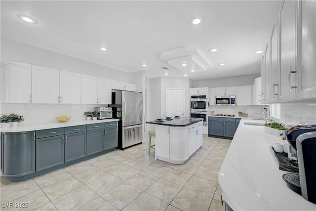 4651 Munich Ct, Las Vegas, NV 89147 - kitchen with appliances with stainless steel finishes, white cabinets, a center island, light tile patterned flooring, and light stone countertops