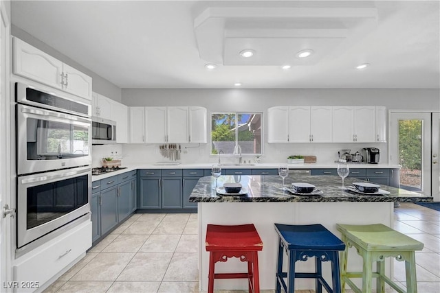 4651 Munich Ct, Las Vegas, NV 89147 - kitchen with stainless steel appliances, white cabinetry, a kitchen bar, light tile patterned floors, and recessed lighting